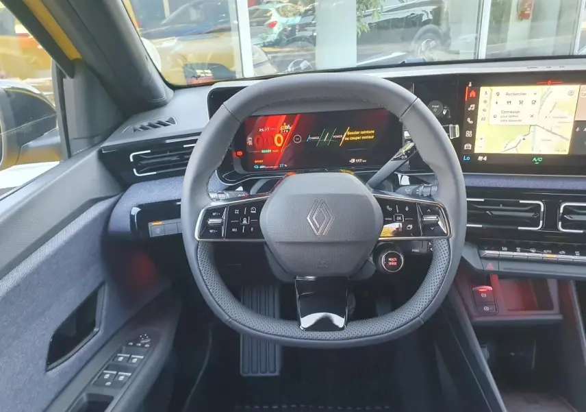 Vue intérieure centrée sur le volant noir de la Renault R5 E-TECH jaune, avec tableau de bord digital et écran tactile.