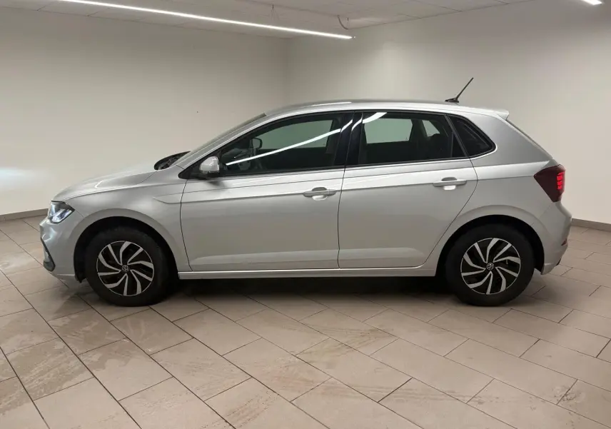 Profil droit d'une Volkswagen Polo 2024 en peinture métallisée Reflet d'argent, avec jantes au design moderne et feux arrière allumés.