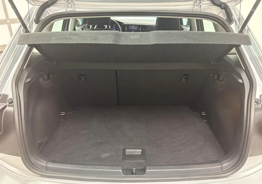 Coffre ouvert d'une Volkswagen Polo 2024 Reflet d'argent, vue arrière montrant l'espace de chargement vide et la tablette arrière relevée.