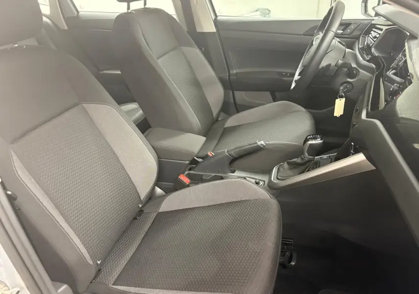 Vue intérieure côté conducteur de la Volkswagen Polo 2024 avec sièges tissu gris et console centrale noire.