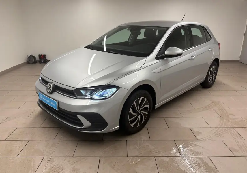 Volkswagen Polo 2024 couleur Reflet d'argent vue 3/4 avant droit avec phares allumés en intérieur.