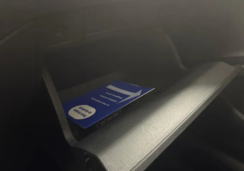 Gros plan sur la boîte à gants ouverte de la Volkswagen Polo 2024 avec un manuel bleu à l'intérieur, intérieur noir.