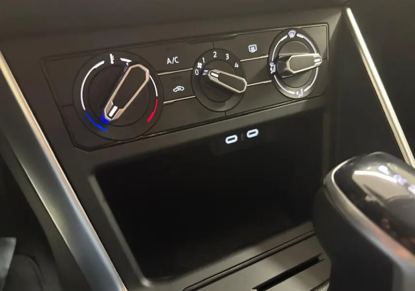 Gros plan sur les commandes de climatisation et la console centrale noire d'une Volkswagen Polo 2024, boîte auto.