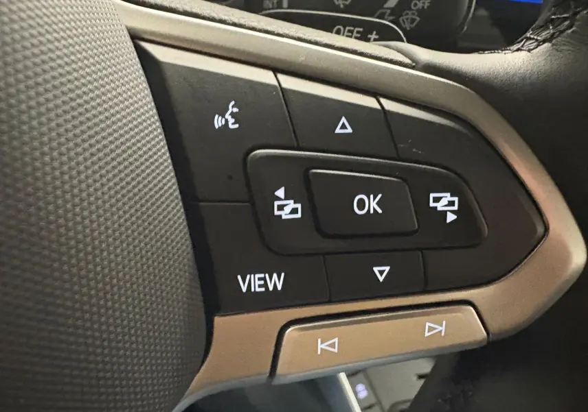 Gros plan sur les commandes au volant côté gauche du Volkswagen Polo 2024 en finition Life, avec boutons noirs et cadre argenté.