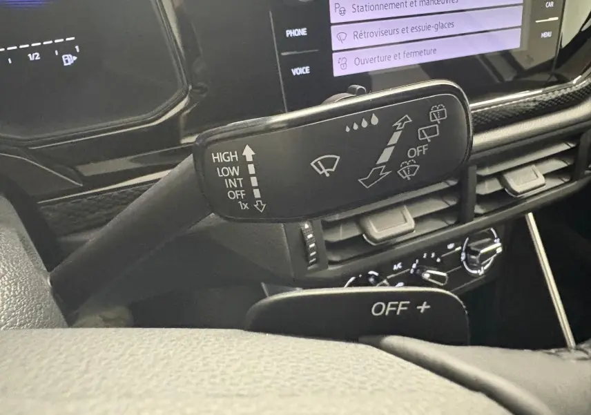 Gros plan sur la commande d'essuie-glace du Volkswagen Polo 2024, intérieur noir avec écran tactile affichant les réglages.