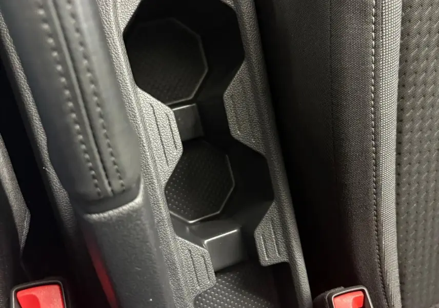 Gros plan sur la console centrale noire avec porte-gobelets et bouton 12V dans une Volkswagen Polo 2024.