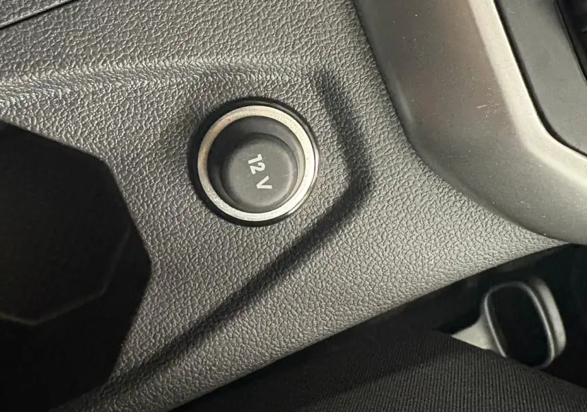 Prise 12V en gros plan sur la console centrale noire du Volkswagen Polo 2024 finition Life.