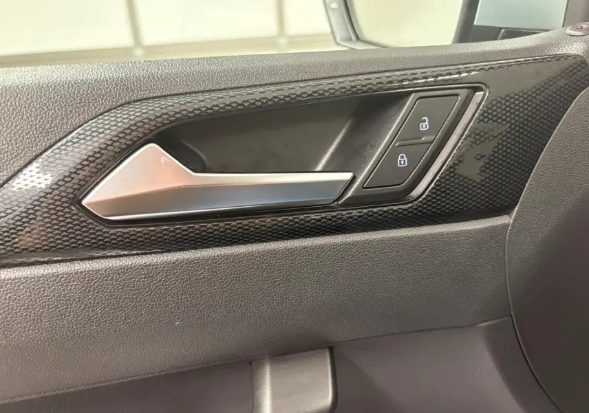 Poignée intérieure côté droit de la Volkswagen Polo 2024 avec finition noire texturée et boutons de verrouillage.