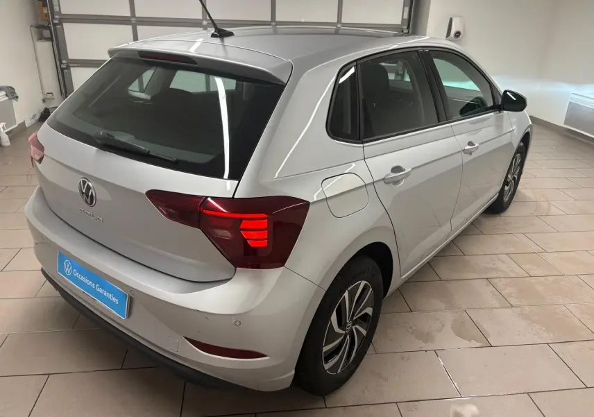 Volkswagen Polo 2024 argent métallisé vue 3/4 arrière droit avec feux arrière allumés en intérieur showroom.