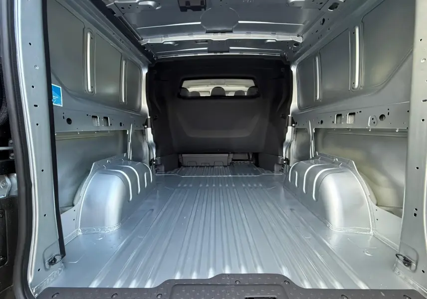 Vue rapprochée du volant noir et du tableau de bord du Renault Trafic cabine approfondie gris Highland, avec levier de vitesses manuel visible.