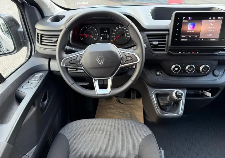 Gros plan sur le levier de vitesses manuel noir avec marquages blancs dans l'habitacle du Renault Trafic gris Highland.