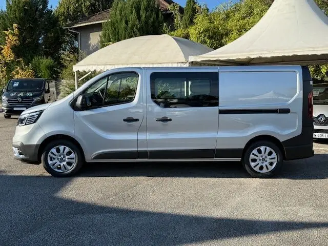 Vue 3/4 avant d’un Renault Trafic cabine approfondie gris Highland 2025 avec calandre noire et feux LED distinctifs.