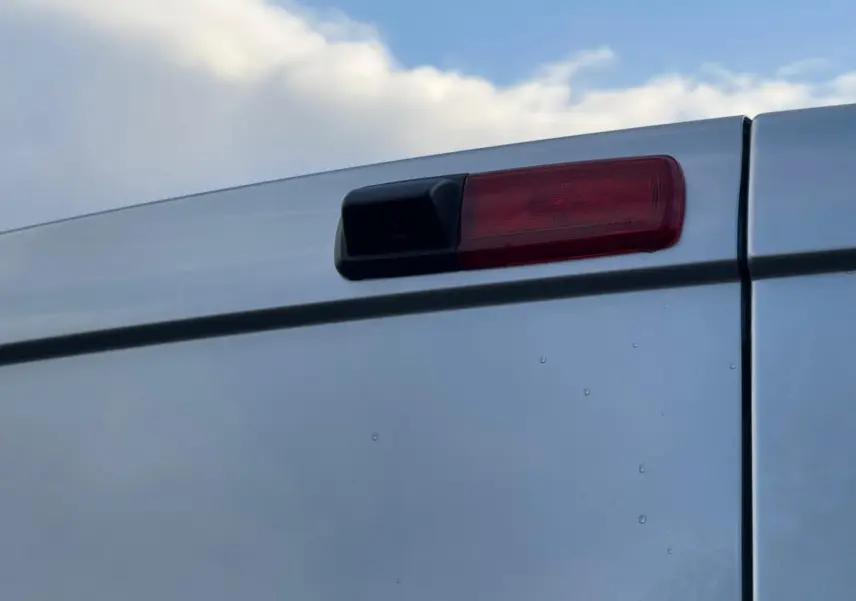 Vue arrière d'un Renault Trafic cabine approfondie gris Highland, portes battantes fermées, éclairage LED vertical visible.