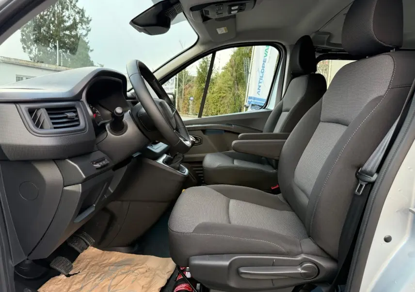 Vue intérieure côté conducteur du Renault Trafic cabine approfondie 2025, sièges gris et tableau de bord noir.