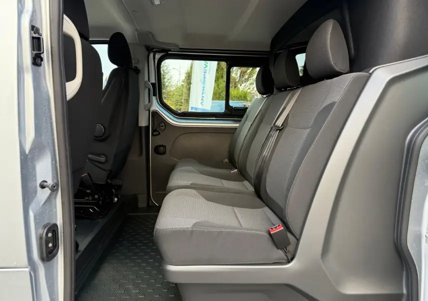 Vue latérale intérieure montrant la banquette arrière grise du Renault Trafic Cabine Approfondie L2H1 2025 avec porte ouverte.