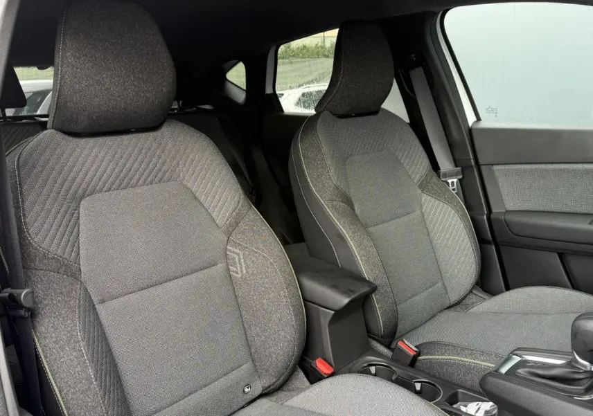 Vue intérieure des sièges avant gris foncé avec surpiqûres jaunes du Renault Captur hybride 2025, côté droit visible.