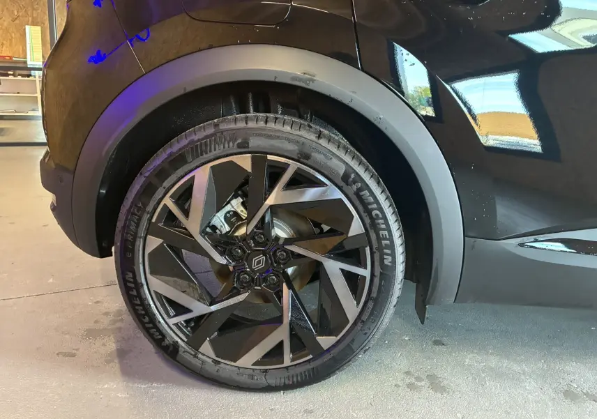 Gros plan sur la roue arrière gauche du Renault Captur noir étoile métal avec jante alliage au design géométrique.