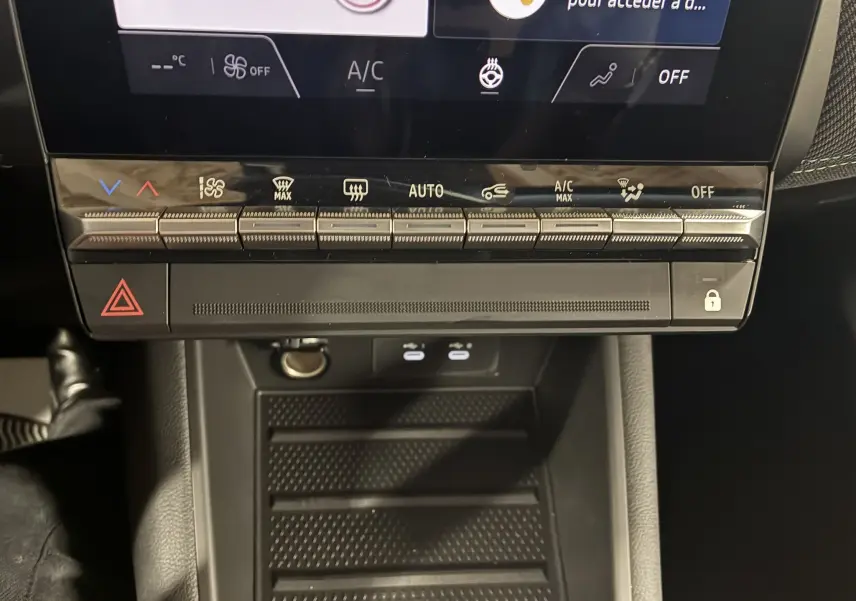 Gros plan sur la console centrale du Renault Captur E-Tech 2025, montrant les commandes tactiles de climatisation et le rangement noir mat.