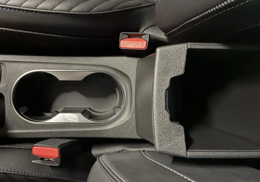 Vue rapprochée de la console centrale noire avec porte-gobelets et accoudoir ouvert du Renault Captur E-Tech 2025.