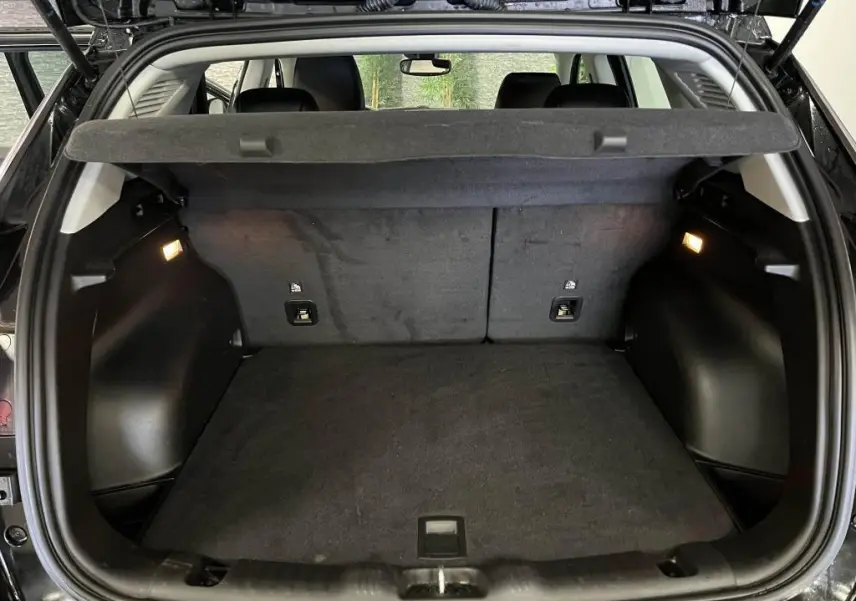 Coffre ouvert vu de l'arrière d'un Jeep Compass noir 2024, espace de chargement propre et éclairé.