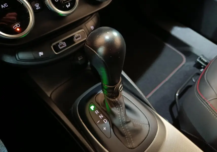 Gros plan sur le levier de vitesse automatique noir de la FIAT 500X 2021, avec coutures apparentes et console environnante.