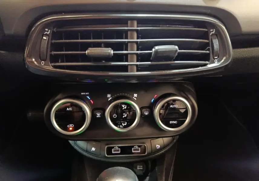 Vue rapprochée du tableau de bord noir de la Fiat 500X 2021, montrant les commandes de climatisation et les aérateurs.