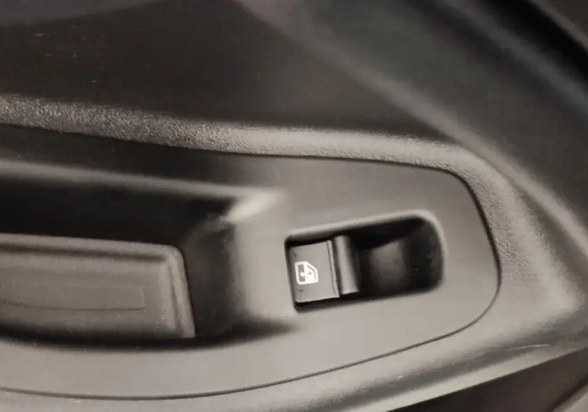 Gros plan sur le bouton de commande de lève-vitre électrique côté conducteur d'une FIAT 500X noire.