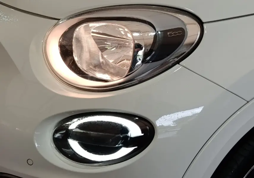 Gros plan sur le phare avant droit blanc de la FIAT 500X avec feu de jour LED en anneau lumineux.
