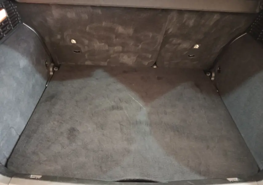 Coffre vide vu de dessus d'une FIAT 500X noir, montrant la moquette et les parois intérieures du coffre.