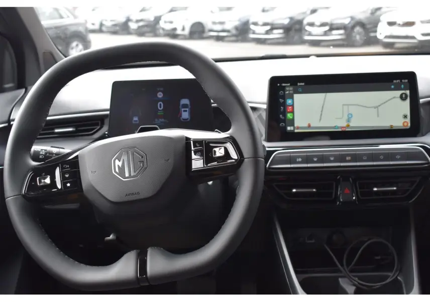 Vue intérieure centrée sur le volant MG et le tableau de bord numérique avec écran tactile affichant la navigation.