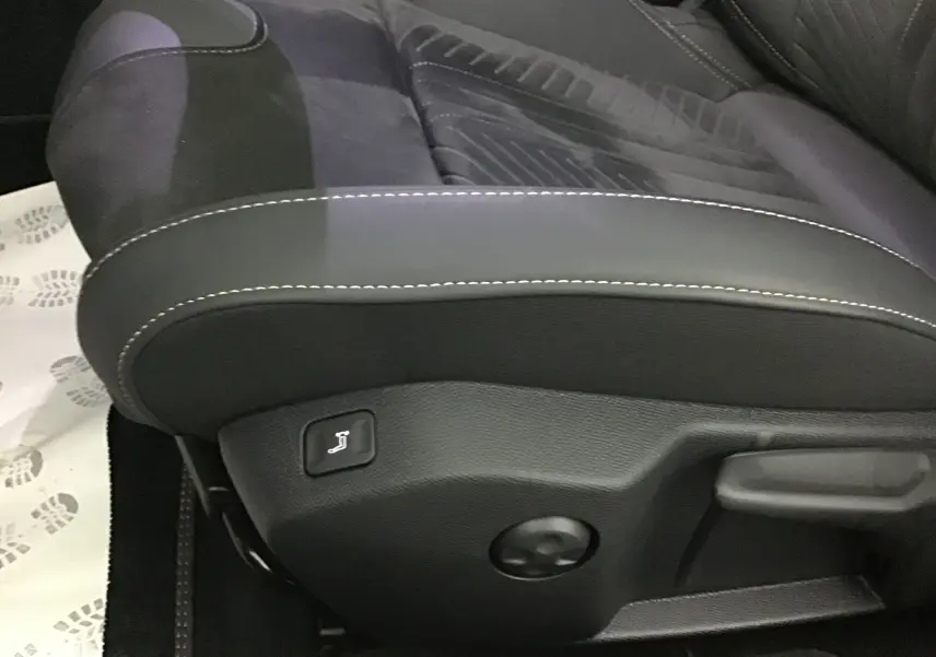 Détail du siège avant gauche en tissu et cuir noir avec surpiqûres blanches dans une Peugeot 508 SW gris Artense.