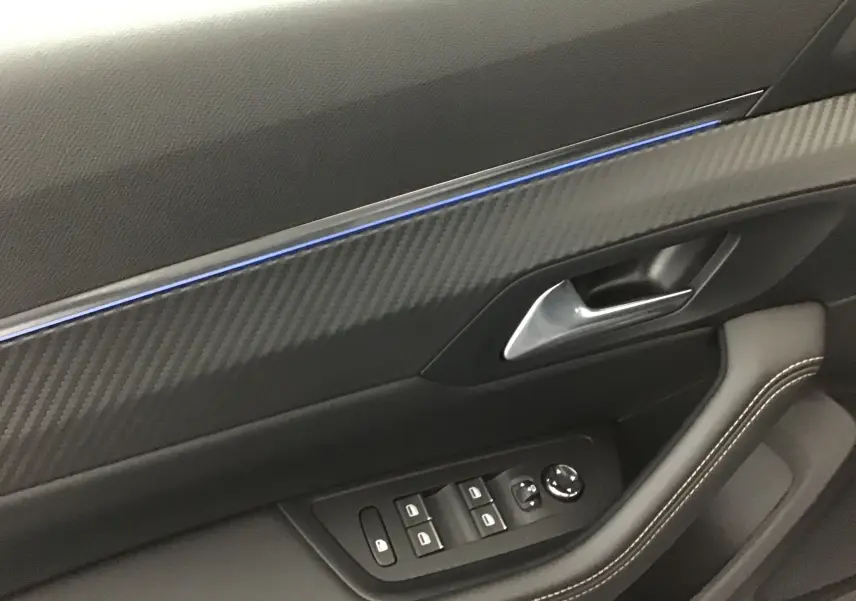 Gros plan sur la garniture intérieure côté gauche de la porte d'une Peugeot 508 SW gris Artense avec éclairage d'ambiance bleu.