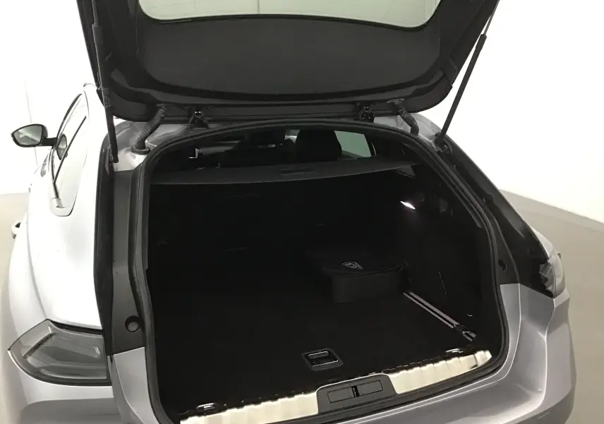 Coffre ouvert vu de l'arrière droit d'une Peugeot 508 SW 2024 gris Artense, espace de chargement spacieux et éclairé.