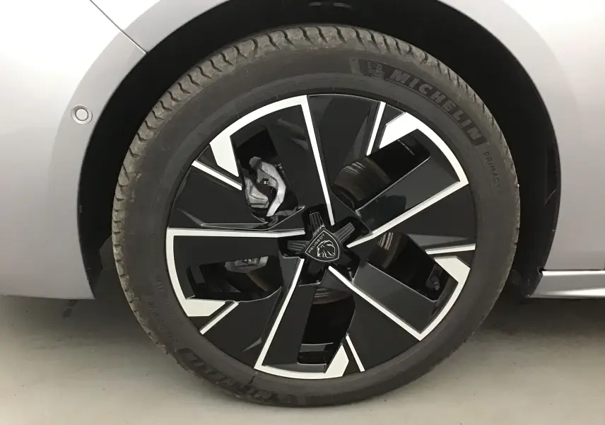 Gros plan sur la roue avant gauche d'une Peugeot 508 SW gris Artense avec jante noire et argentée au design moderne.
