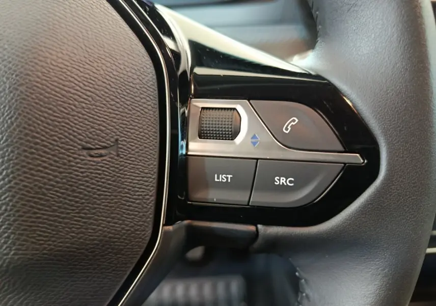 Gros plan sur les commandes gauche du volant en cuir noir du Peugeot 208 PureTech 100 S&S Allure gris foncé.