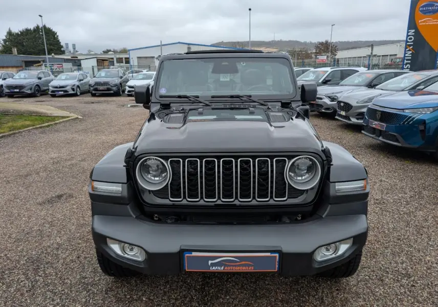 Vue de face du Jeep Wrangler noir avec calandre à sept fentes et phares ronds LED, sur parking extérieur.