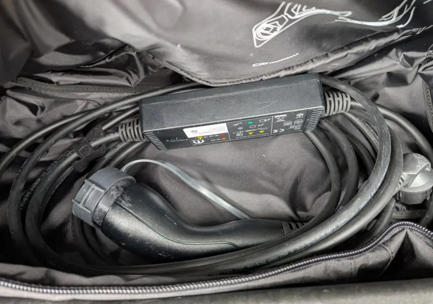 Gros plan sur le câble de recharge noir rangé dans un sac, accessoire du Jeep Wrangler 2024 hybride noir.