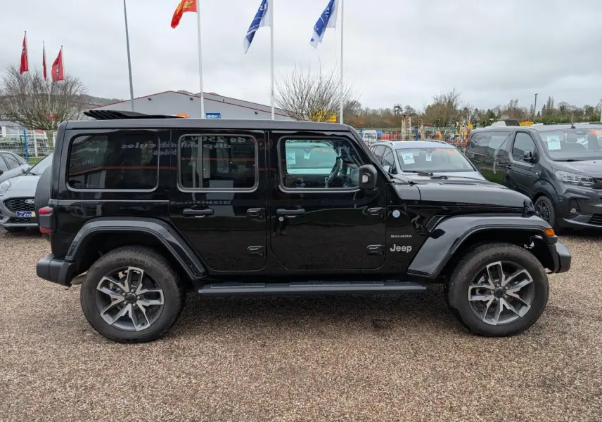 Vue de profil côté gauche d'un Jeep Wrangler Unlimited Sahara noir avec jantes alliage 20 pouces et marchepieds.