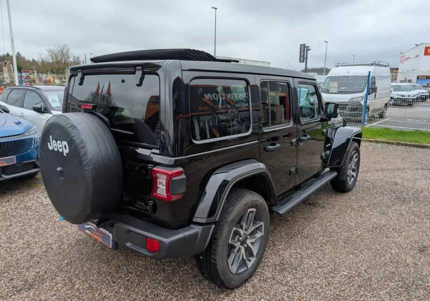 Jeep Wrangler 2024 noir vue 3/4 arrière droit avec roue de secours et marchepied visibles.