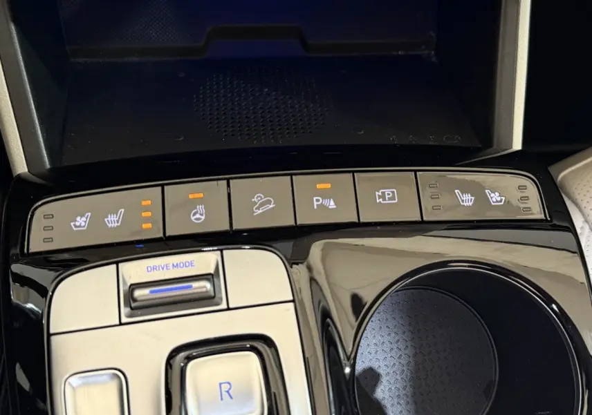 Gros plan sur la console centrale du Hyundai Tucson gris foncé, avec boutons de sièges chauffants et mode de conduite.