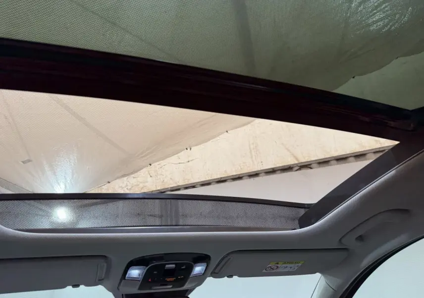 Vue intérieure du toit ouvrant en verre inclinable du Hyundai Tucson gris foncé, avec pare-soleil partiellement déployé.