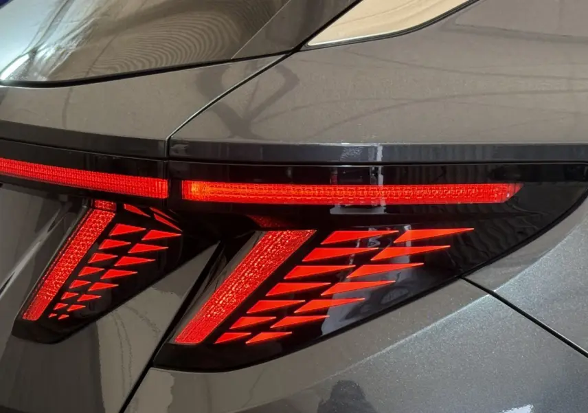 Gros plan sur le feu arrière droit rouge allumé du Hyundai Tucson 1.6 Hybrid 230 Executive gris foncé.