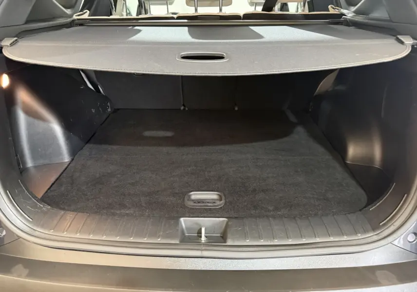 Coffre ouvert vu de l'arrière d'un Hyundai Tucson gris foncé avec cache-bagages et sièges arrière beiges.
