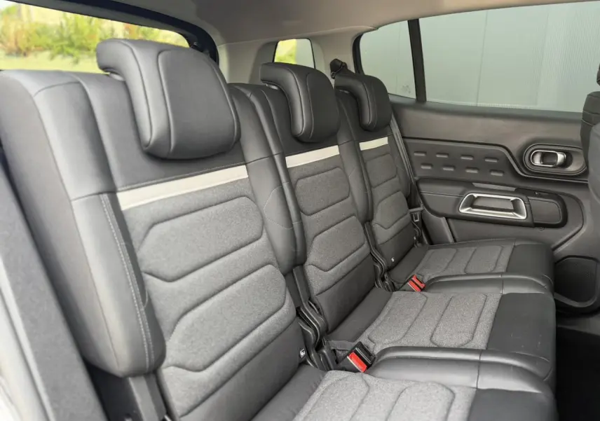 Vue intérieure des trois sièges arrière indépendants gris du Citroën C5 Aircross 2025 avec appuis-tête et ceinture rouge.