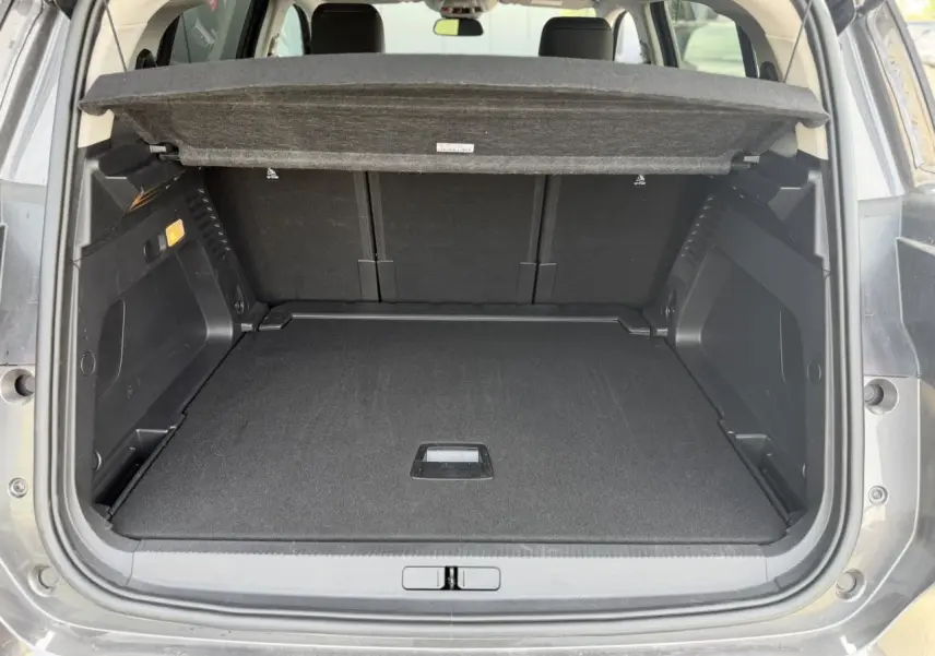 Coffre ouvert vu de l'arrière du Citroën C5 Aircross gris Platinium avec cache-bagages et banquette arrière noire.