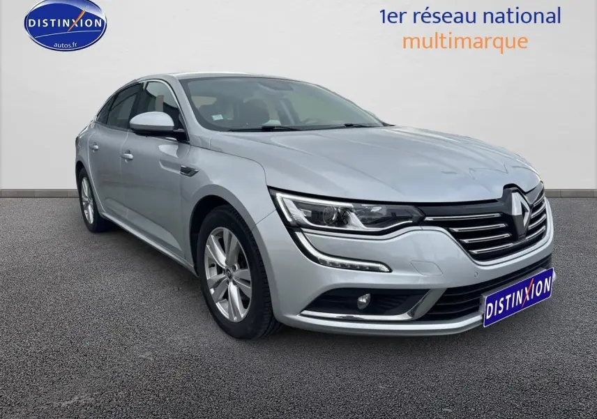 Renault Talisman gris alu en 3/4 avant droit, avec calandre distinctive et jantes alu visibles.