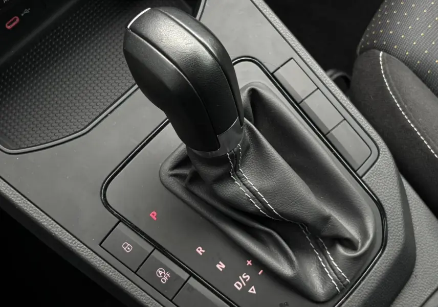 Gros plan sur le levier de vitesses automatique noir avec coutures blanches dans l’habitacle d’une SEAT Ibiza argent urbain.