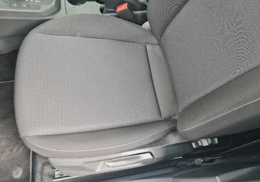 Gros plan sur le siège conducteur en tissu gris foncé de la SEAT IBIZA 2024, avec réglage manuel visible.