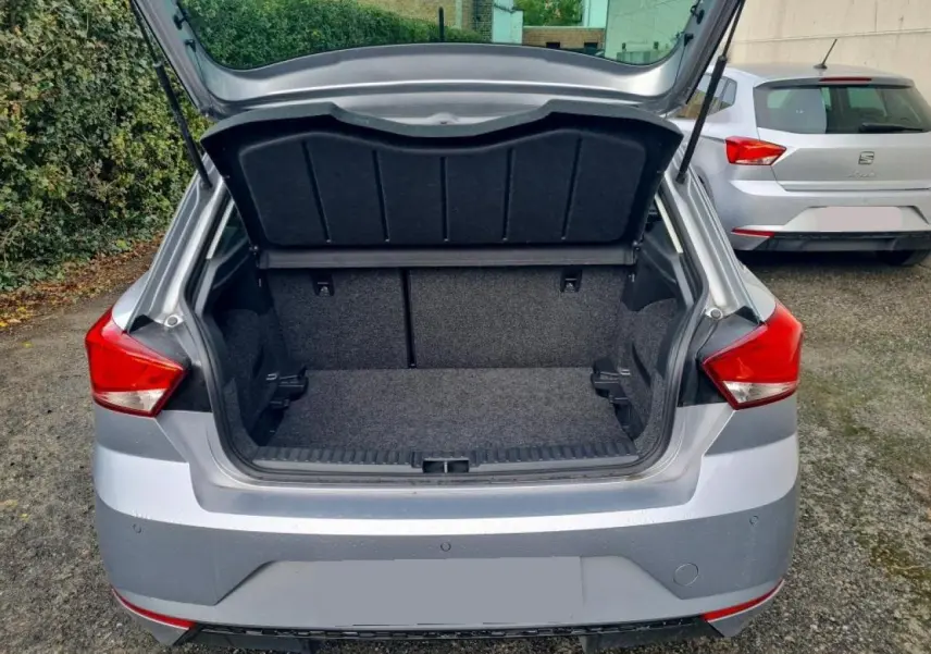 Coffre ouvert vu de l'arrière d'une SEAT Ibiza 2024 argent urbain, avec hayon relevé et intérieur du coffre vide.