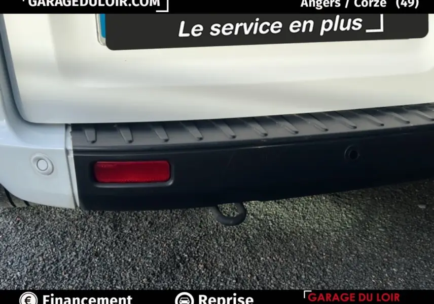Gros plan sur le pare-chocs arrière noir et blanc du Ford Transit Custom Fourgon avec feu rouge et crochet d'attelage visible.